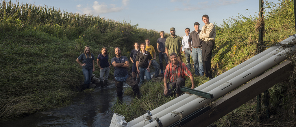 A group of people pose near a water-quality sensor in Clear Creek